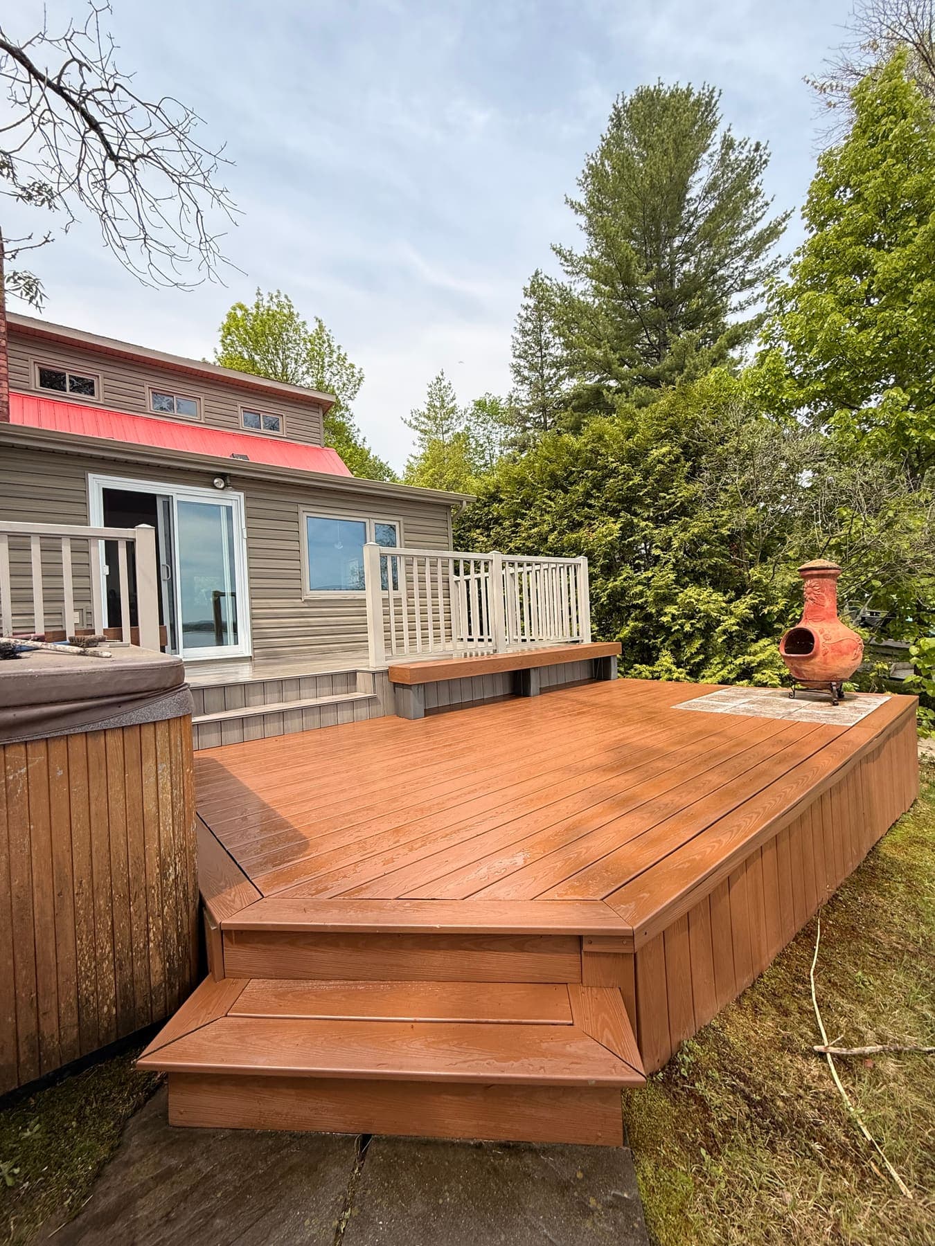 After: a freshly cleaned wood deck with hot tub and chiminea in golden afternoon light.