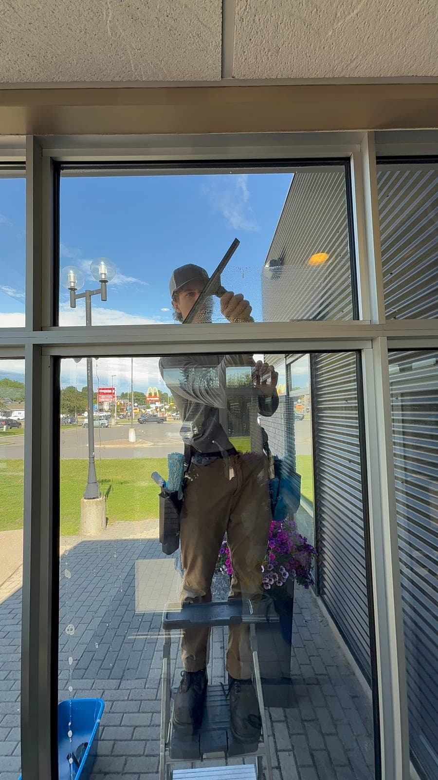 PVS technician squeegeeing a commercial storefront window from inside