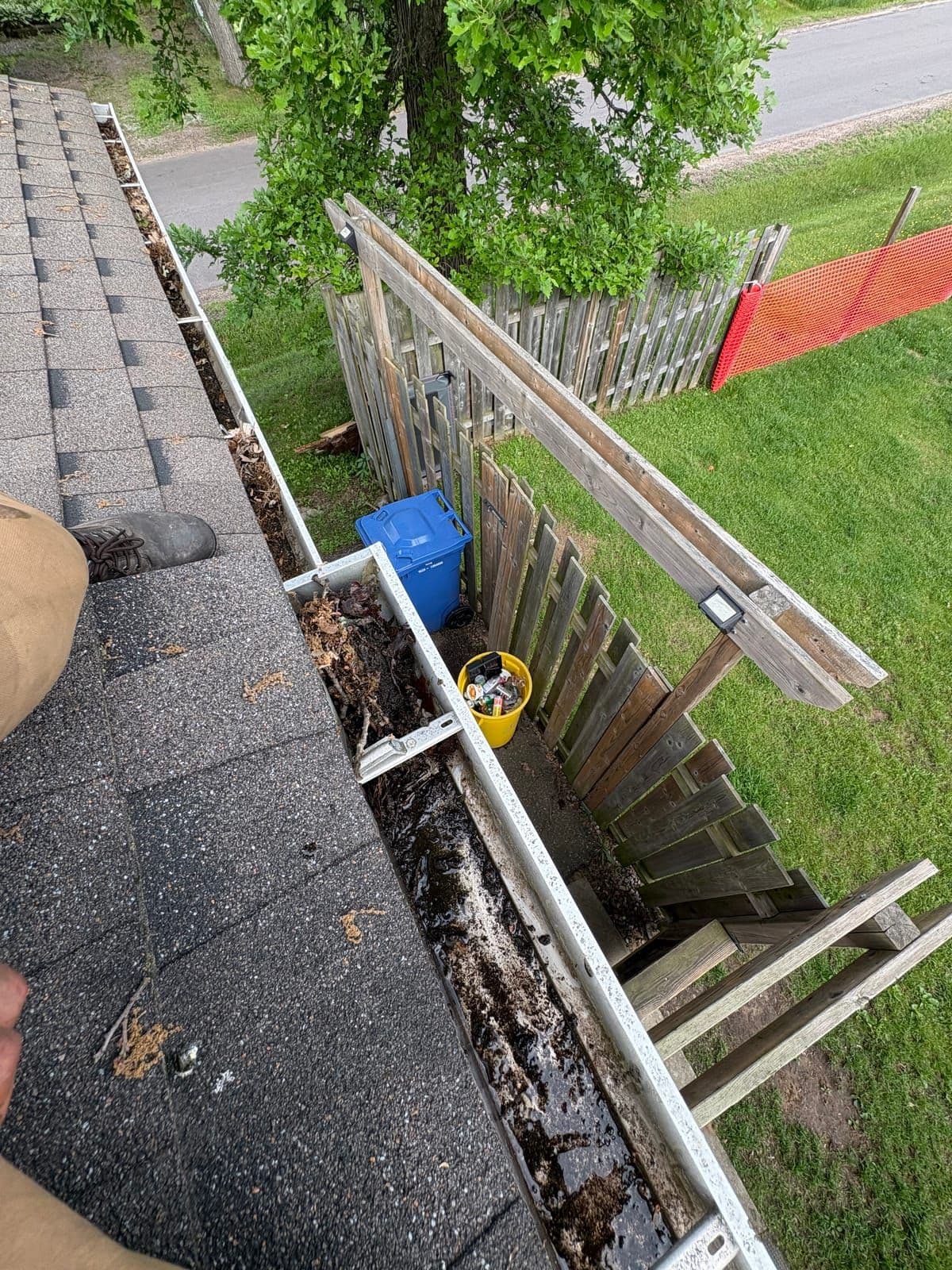 Technician hand-clearing leaves and debris from a residential gutter in the Ottawa Valley