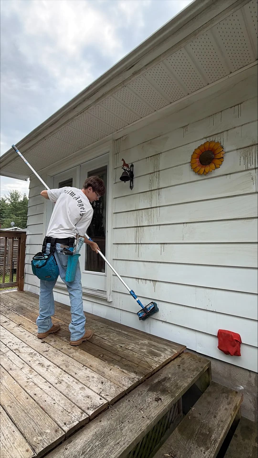 Technician scrubbing dirty siding with a soft-wash brush on an Ottawa Valley home