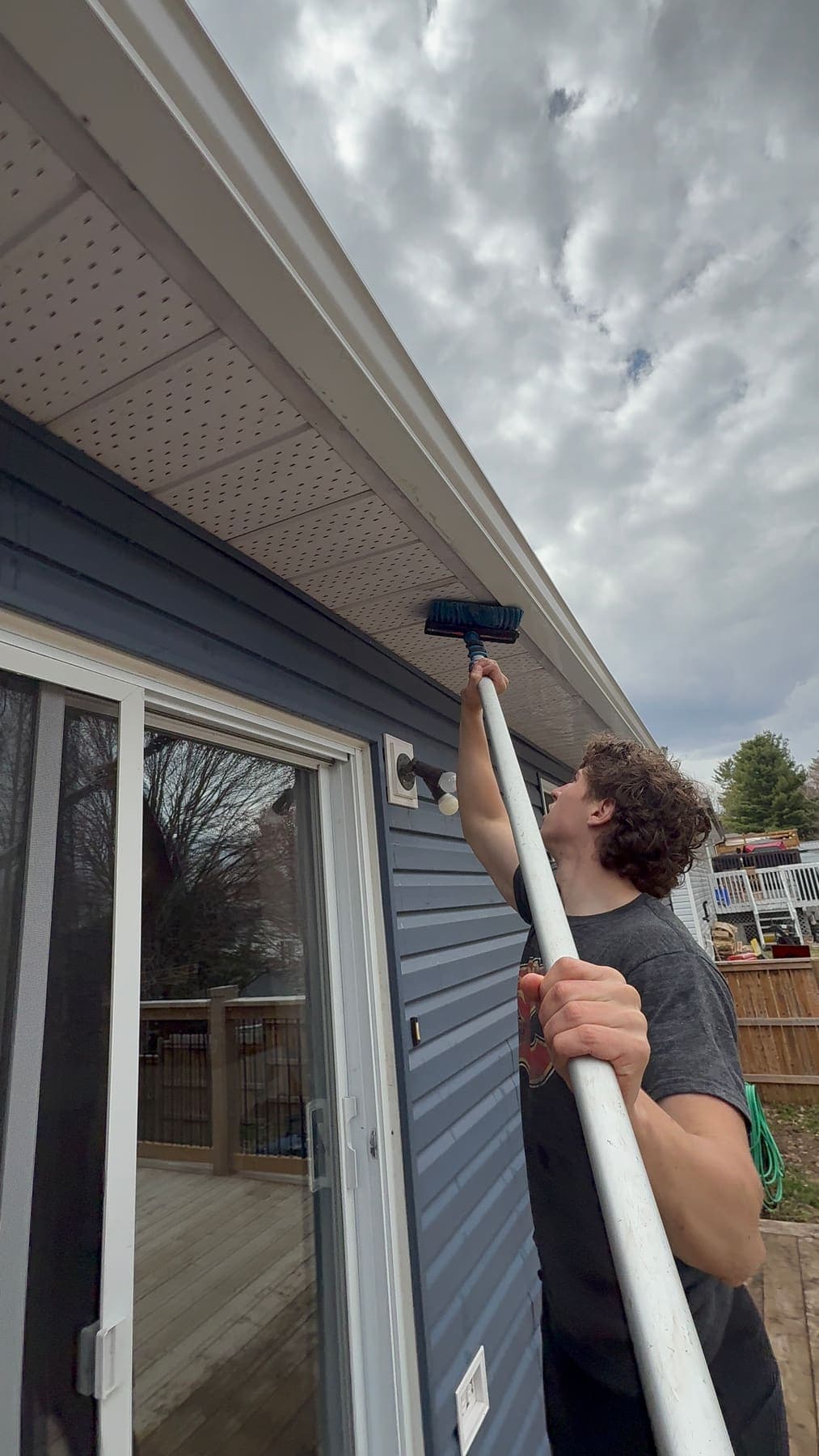 PVS technician soft-washing exterior siding and soffit