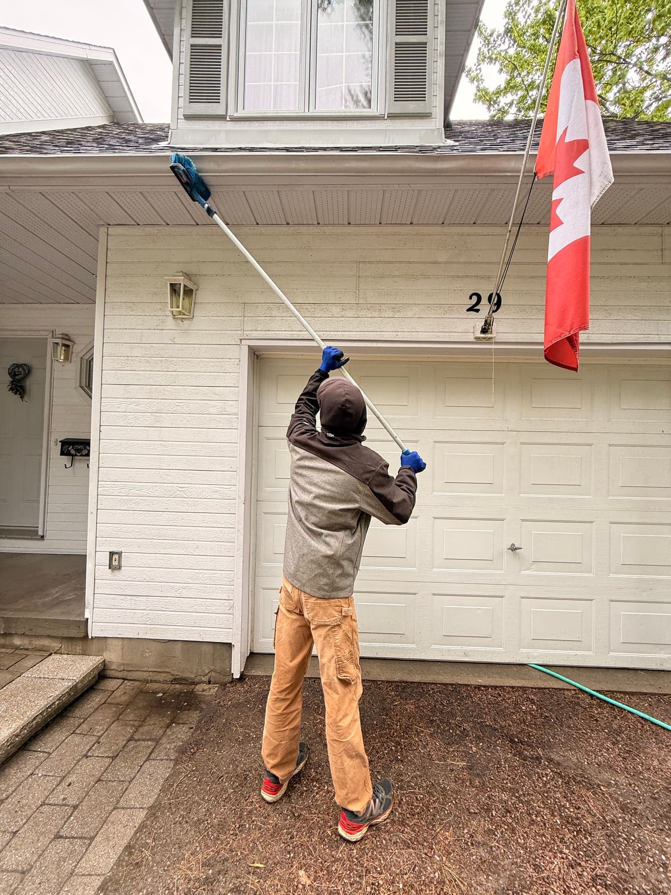 PVS technician soft-washing exterior siding and soffit