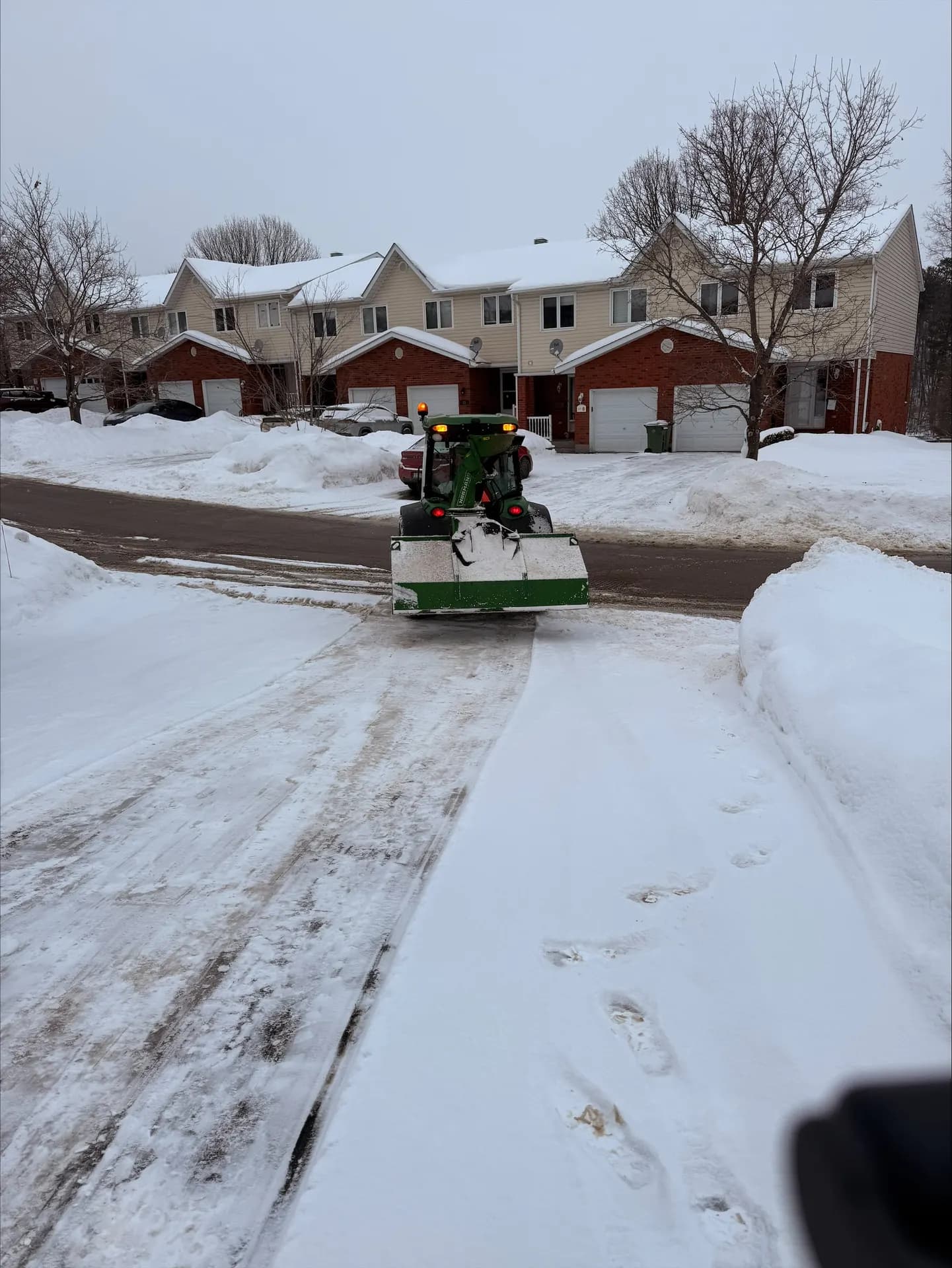 Tractor with box plow clearing a townhouse driveway after a snowfall in Pembroke