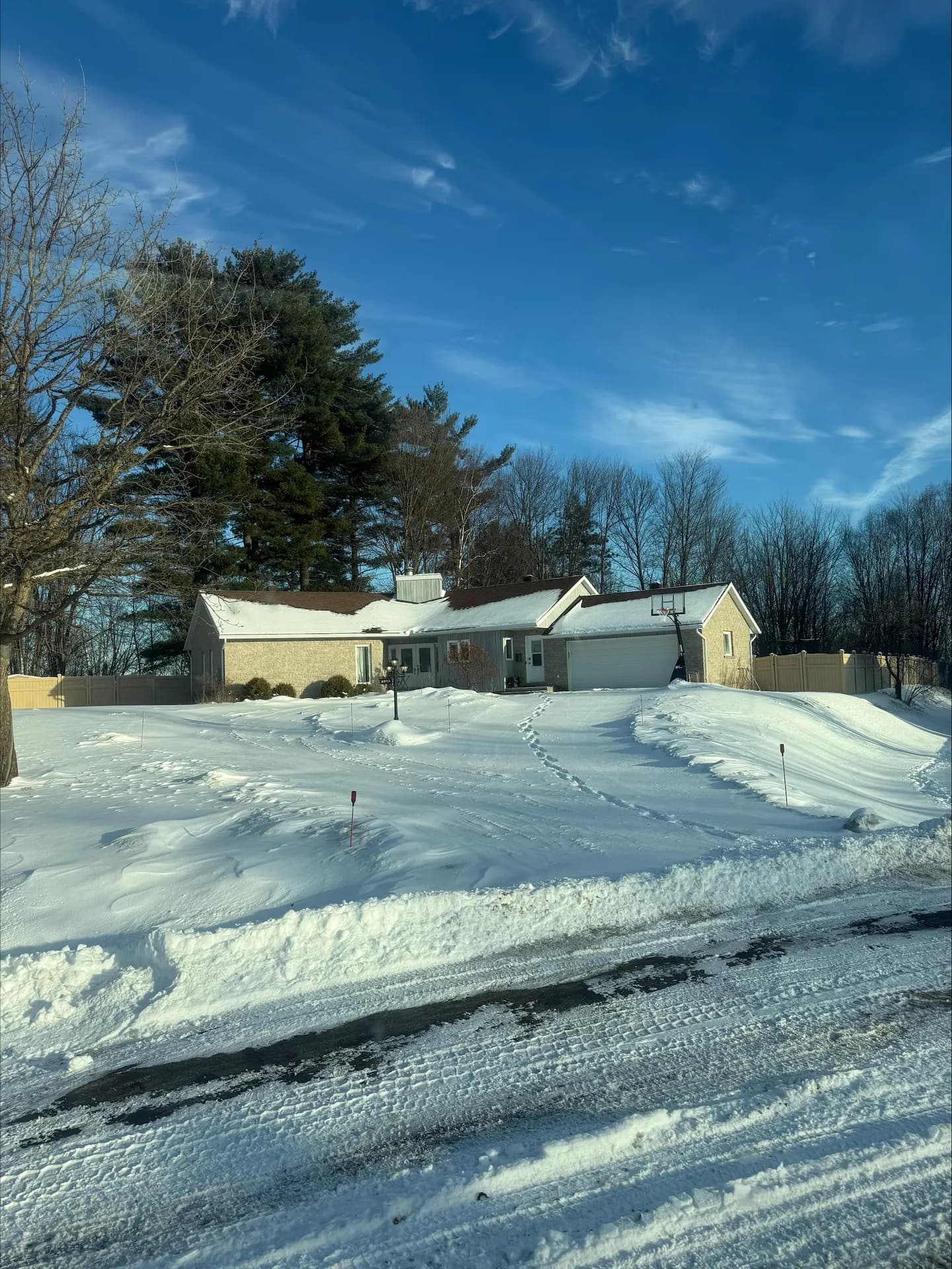 Snow-covered ranch home with a cleared driveway under a blue winter sky near Deep River