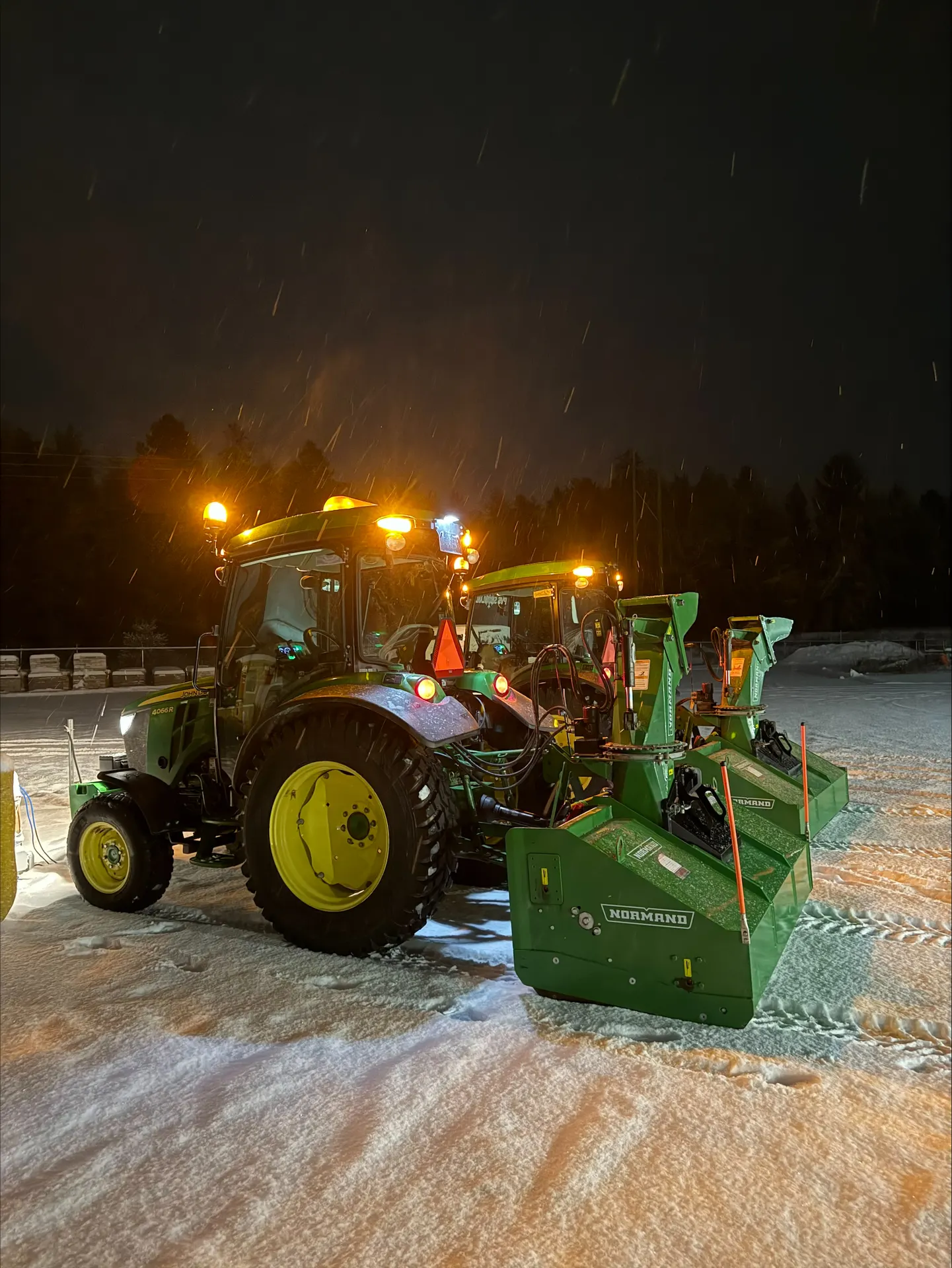 Two PVS tractors with snowblowers staged at night in falling snow, ready for the storm