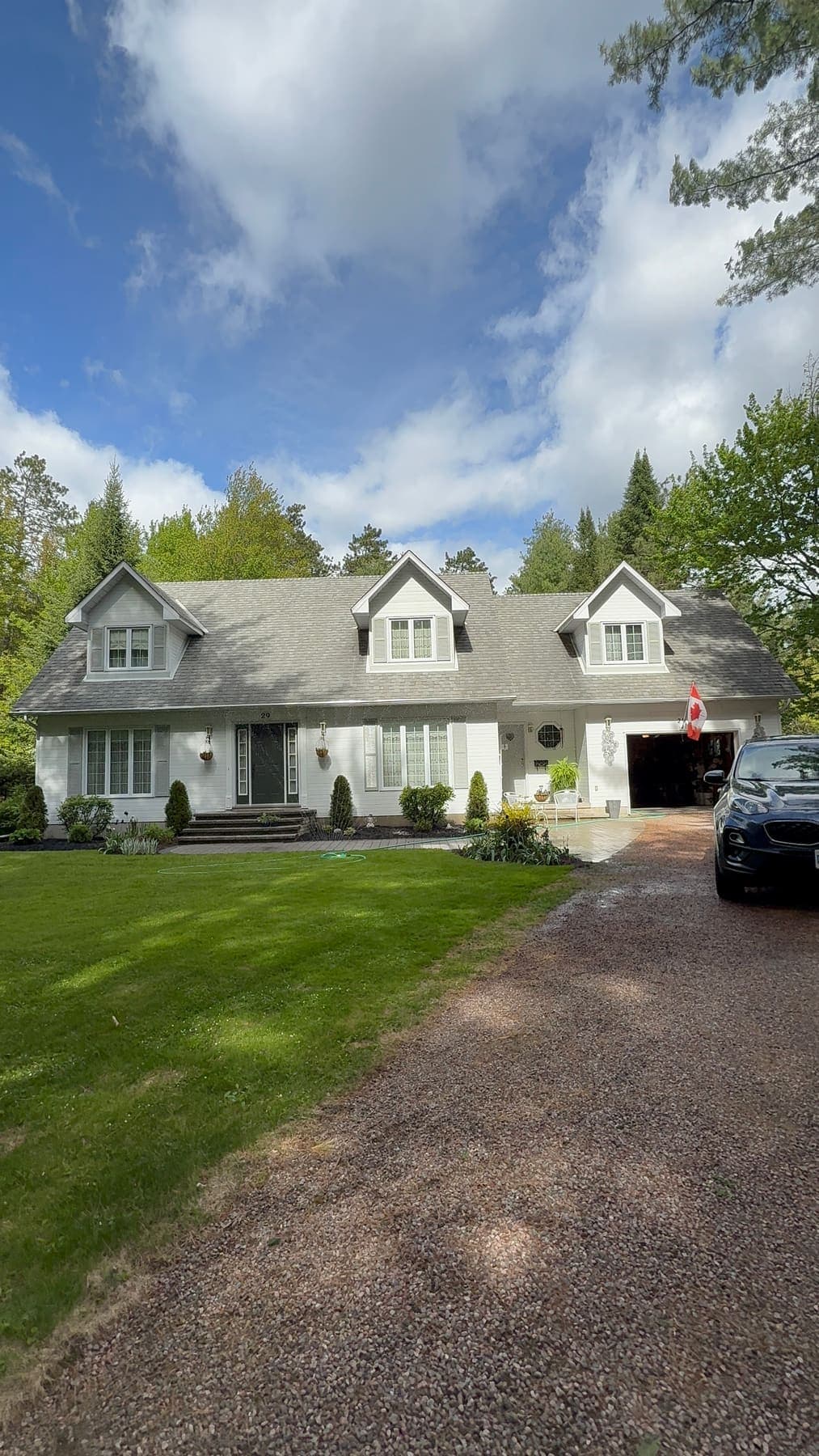 Cleaned exterior of a white Cape Cod home with garden beds
