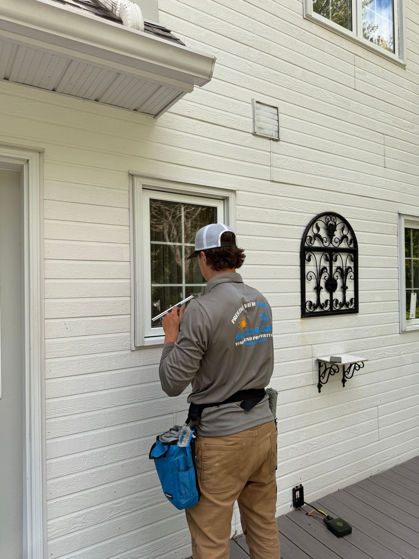 PVS technician in branded uniform cleaning a residential window