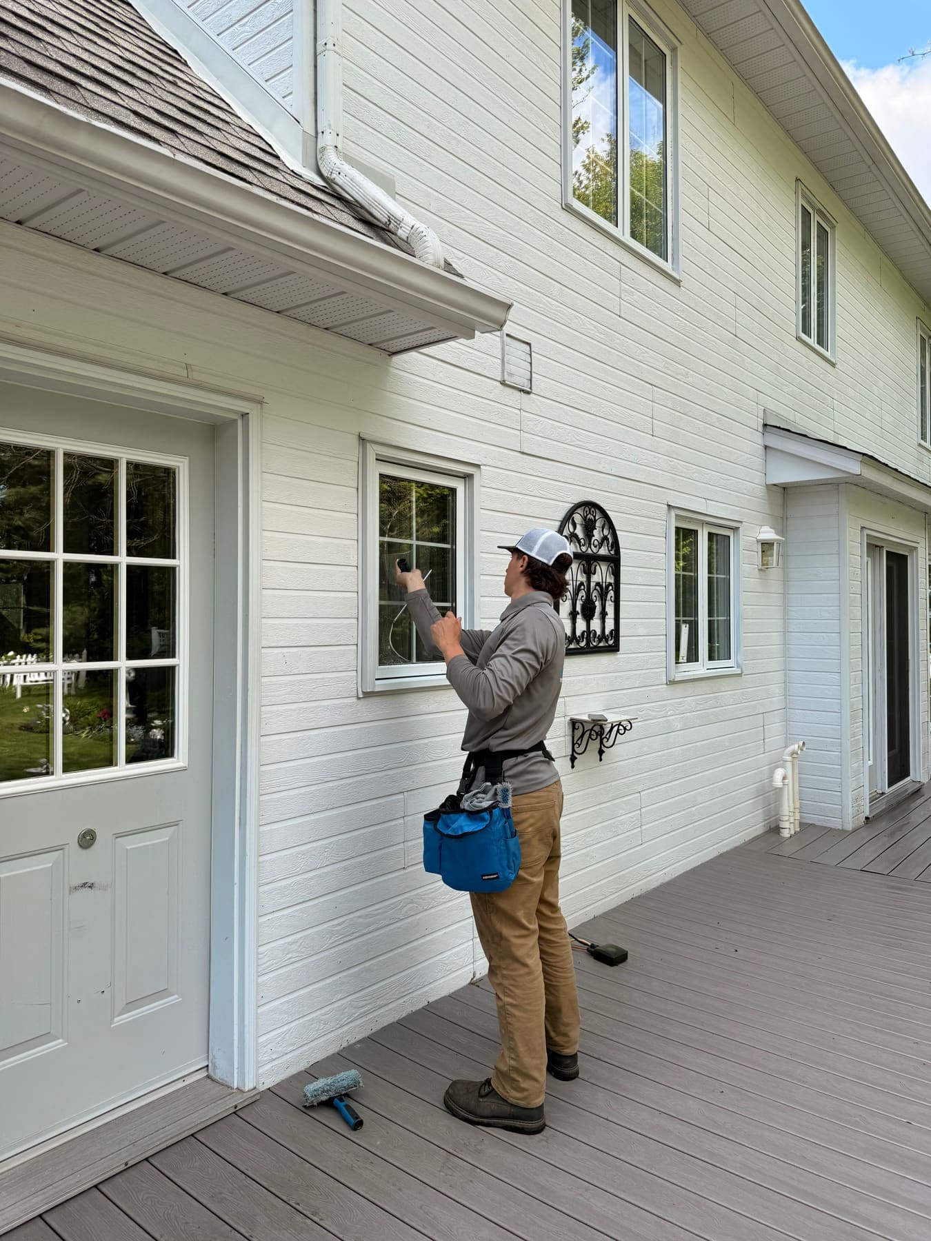 PVS technician on a ladder cleaning a second-story residential window